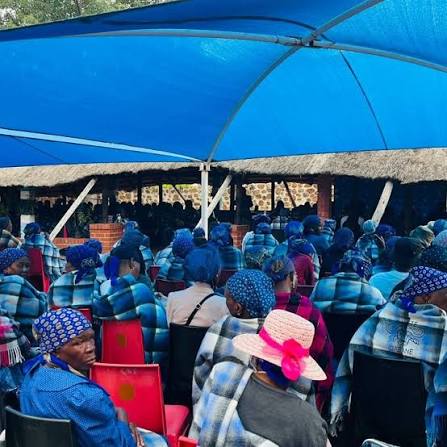 Residents gathered under shade at a community meeting